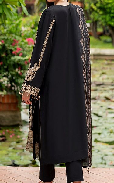 Black outfit with gold embroidery in a garden setting