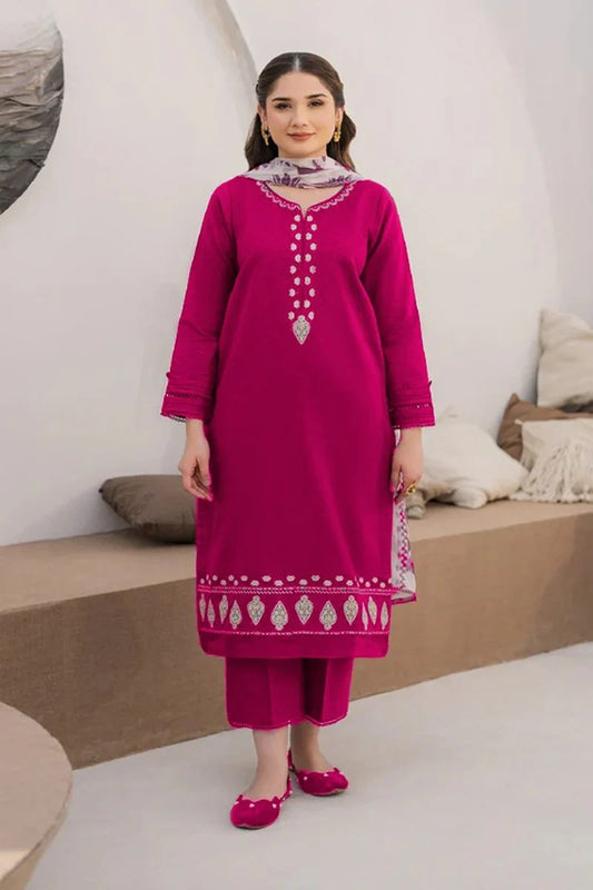Woman wearing a pink traditional outfit with intricate designs in a minimalistic setting.