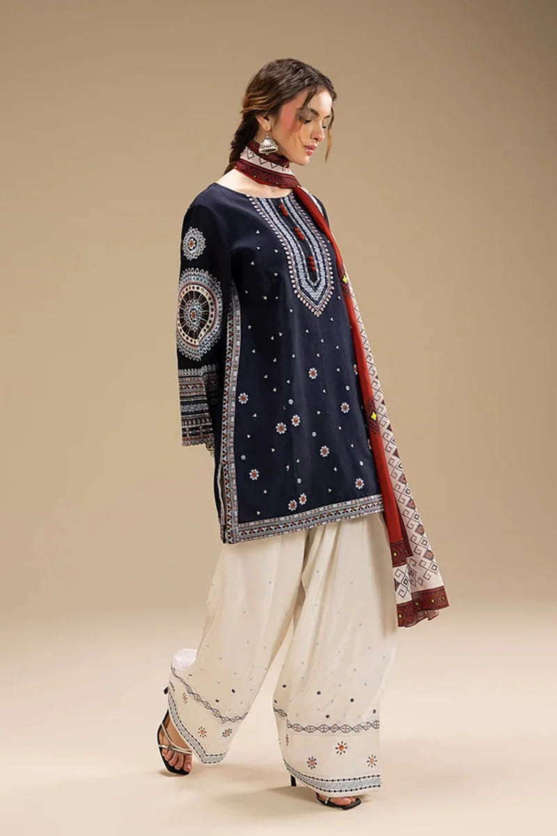Woman wearing a navy blue embroidered top with white pants and a red and white dupatta on a beige background