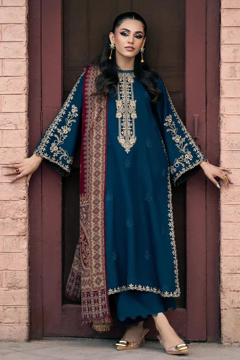 Woman wearing a blue embroidered traditional outfit standing in front of a brick wall.
