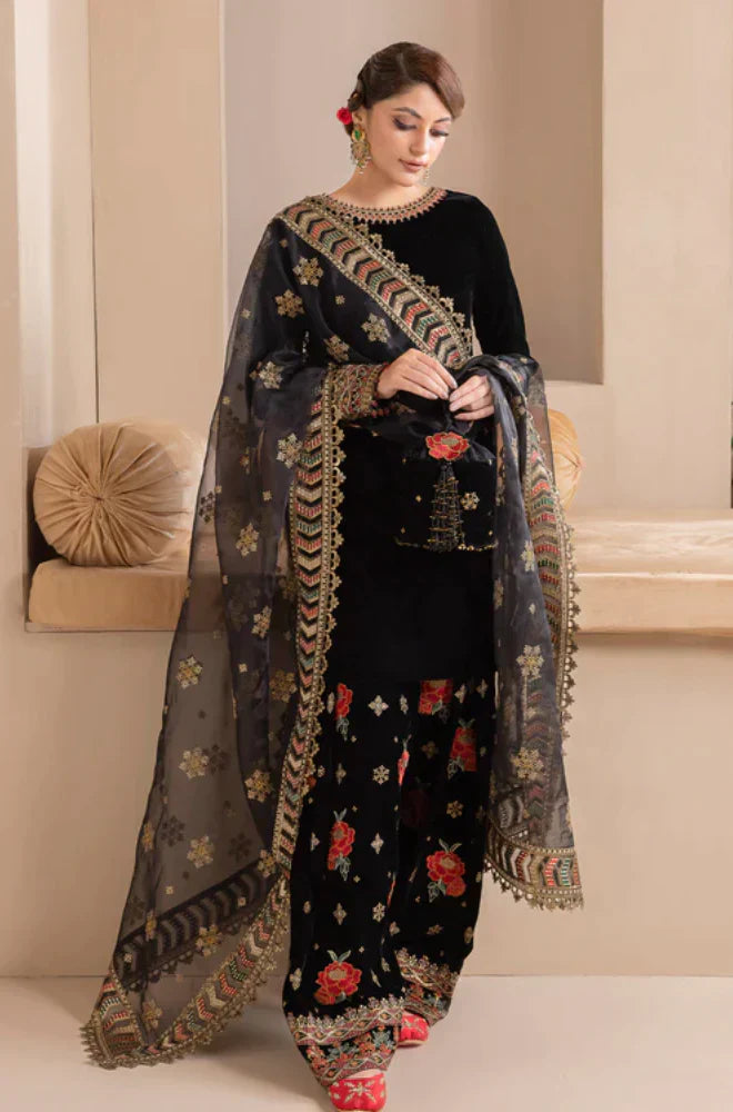 Woman wearing a black embroidered outfit with a matching dupatta in an indoor setting.