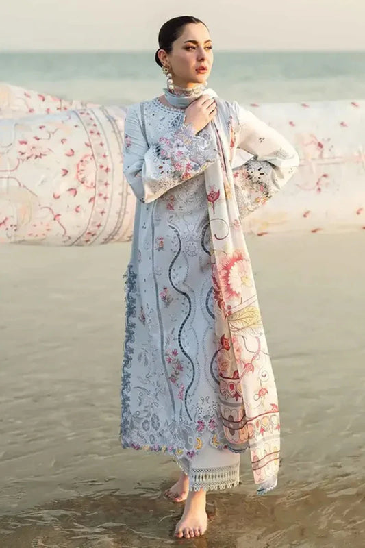 Woman in traditional outfit with floral patterns standing on a beach.