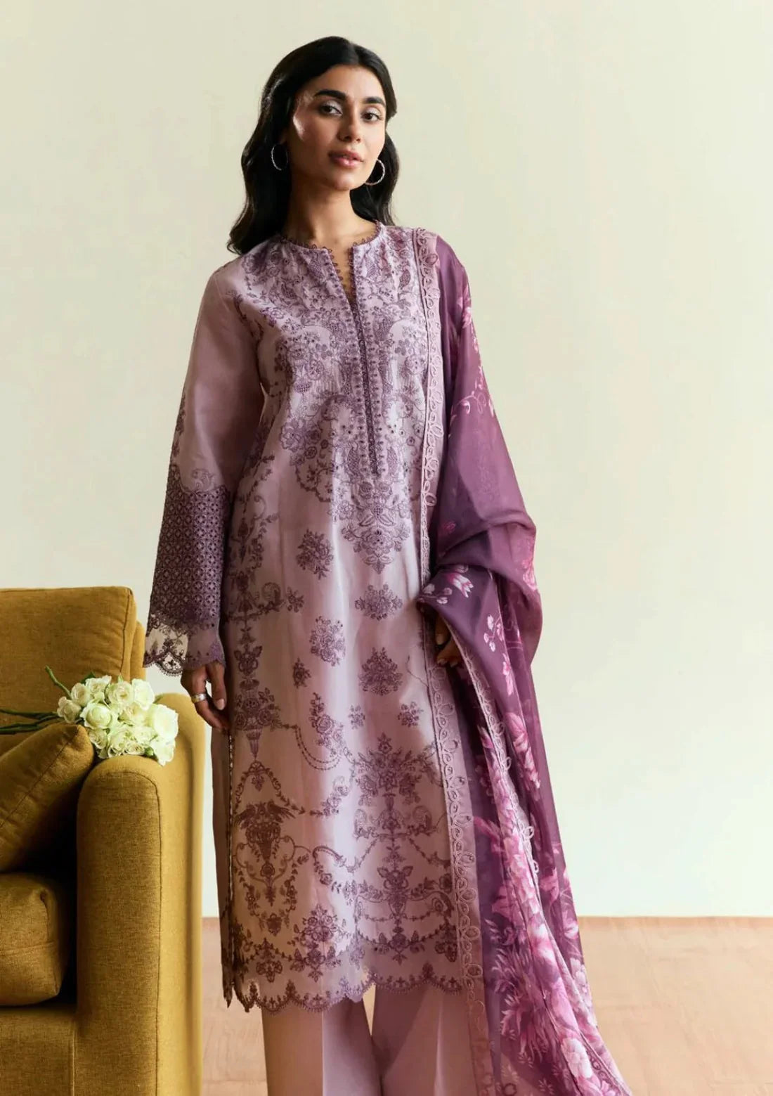 Woman wearing a purple and white patterned outfit with a matching dupatta in a room.