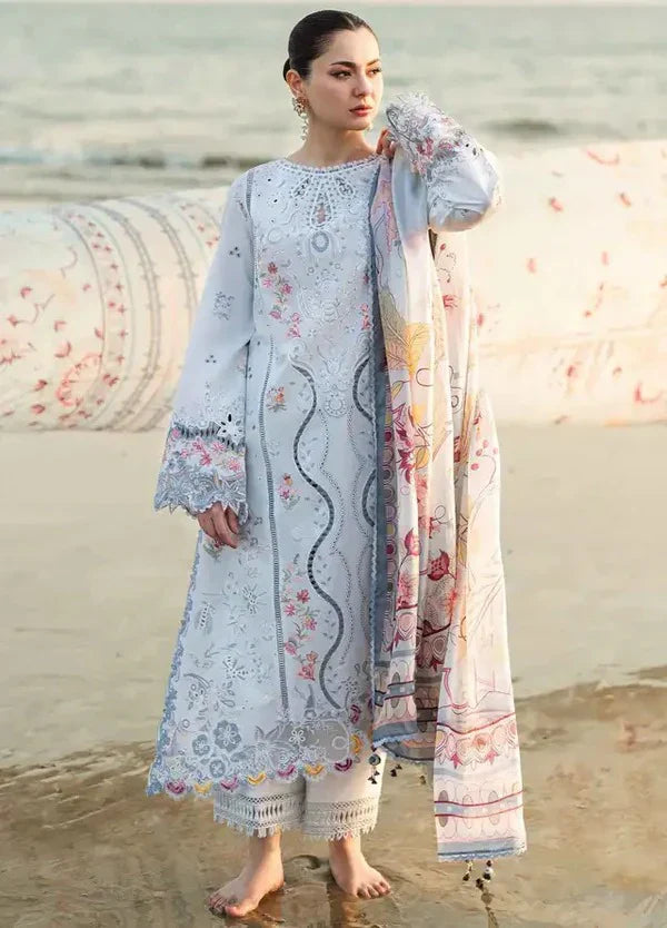 Woman in a floral embroidered outfit standing on a beach.