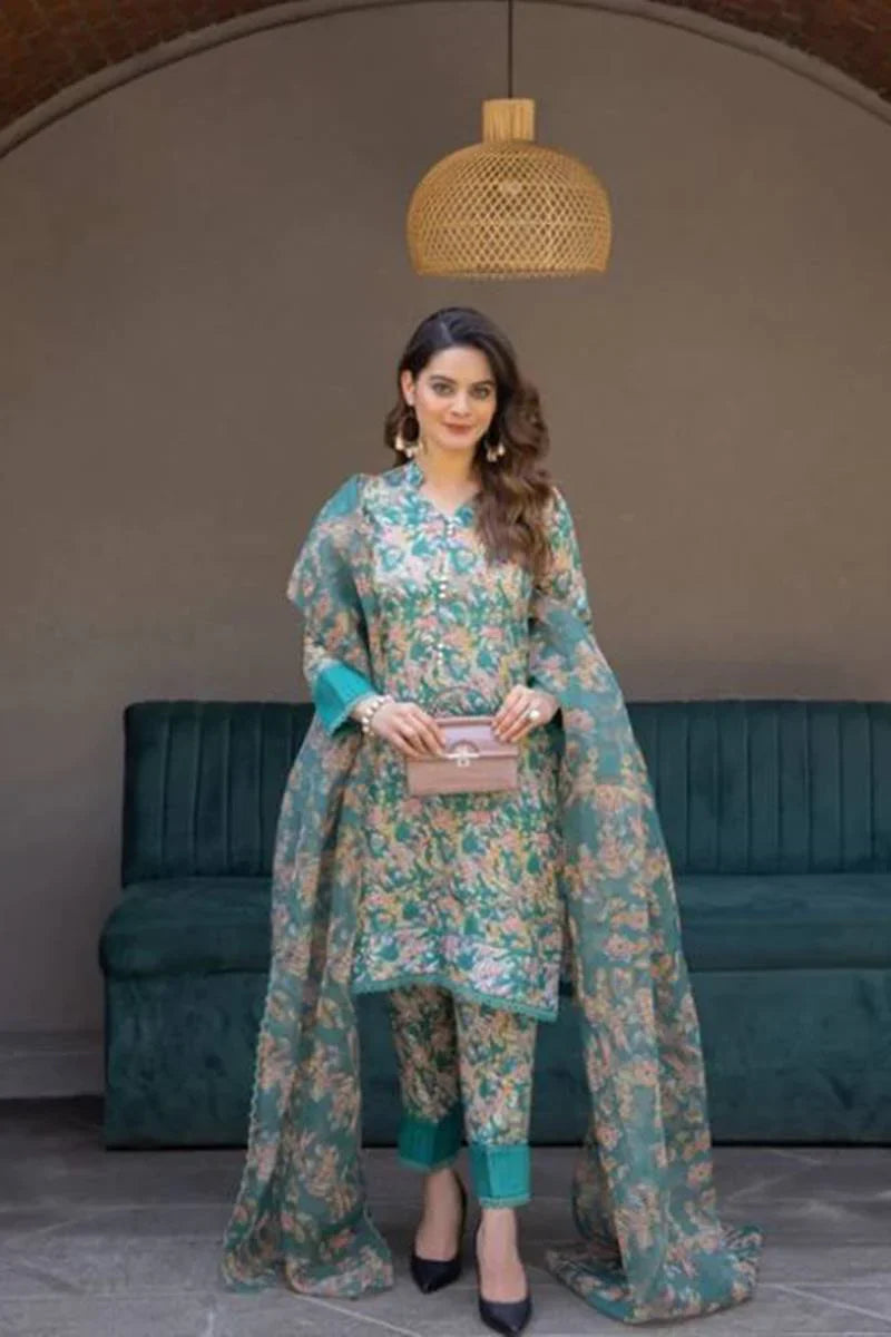 Woman in a floral outfit standing in a room with a teal couch and woven pendant light.