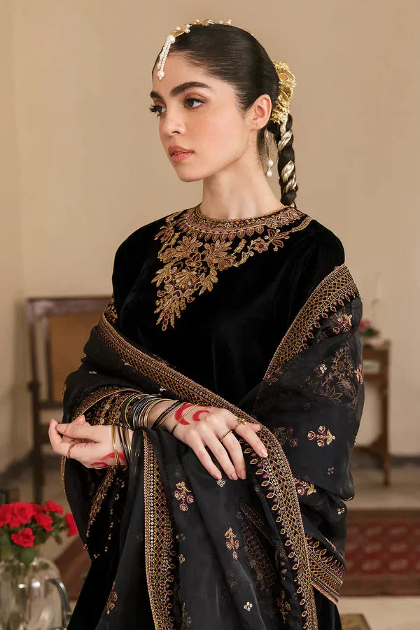 Woman wearing a black and gold traditional outfit with intricate designs.