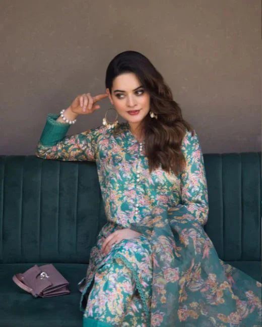 Woman in a floral dress sitting on a teal couch with a gray background