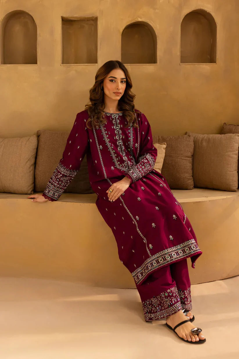 Woman in a maroon traditional outfit sitting on a beige couch with a beige wall background