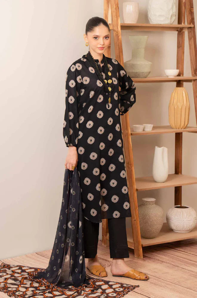Woman wearing a black floral patterned kurta with black pants in a room with wooden shelves.