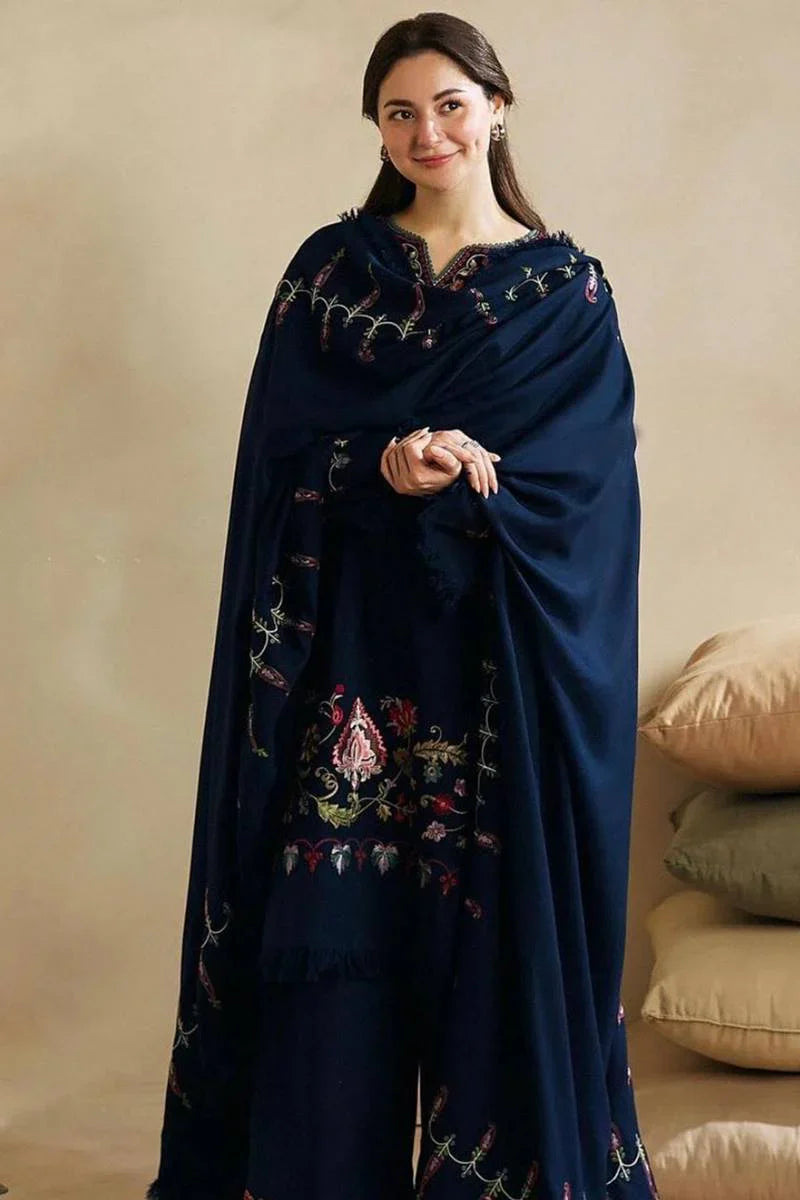 Woman wearing a dark blue embroidered shawl against a beige background