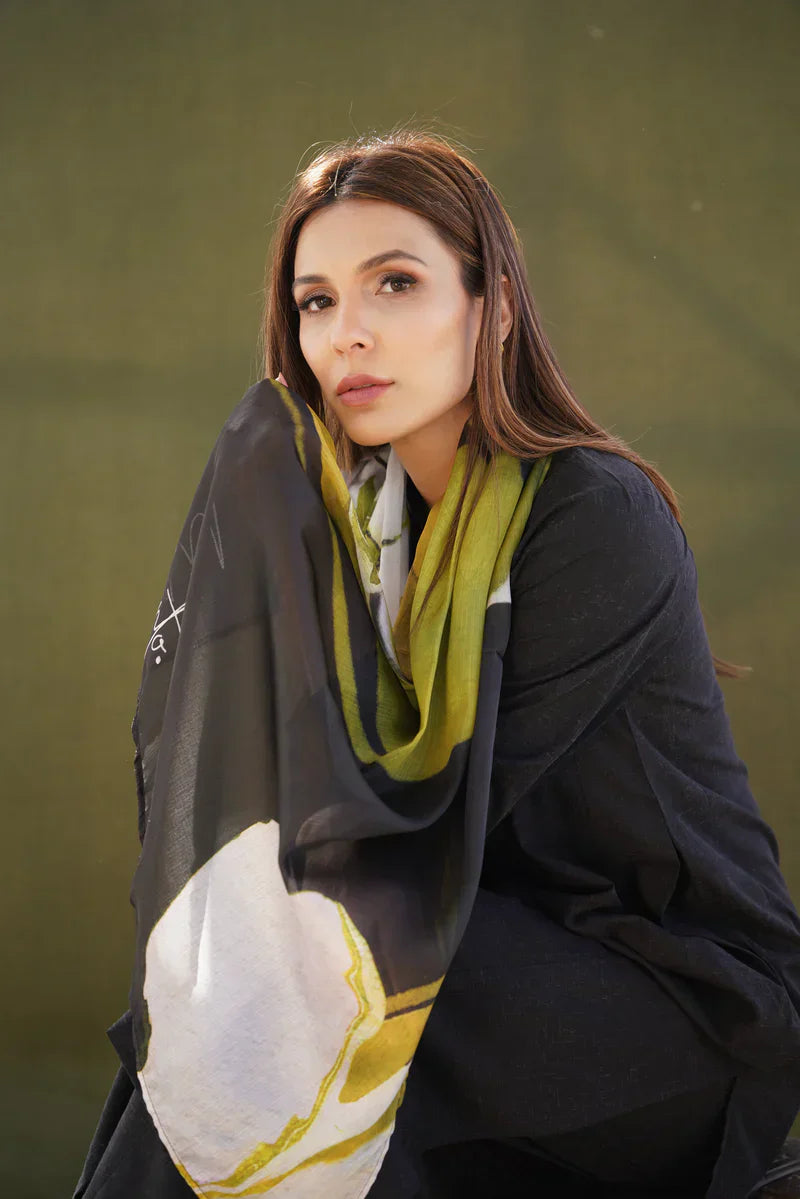 Woman wearing a dark coat with a colorful scarf against a green background