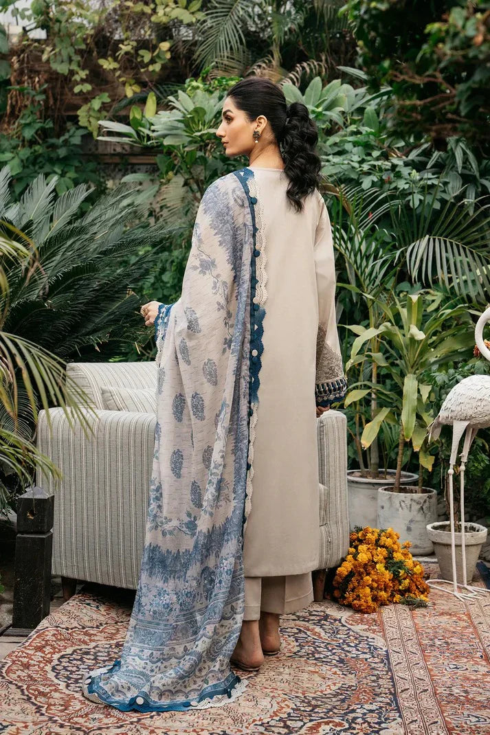Woman in a beige and blue traditional outfit standing in a garden setting.