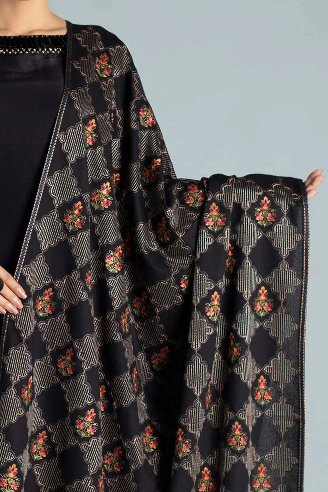 Black floral patterned fabric draped over a person against a gray background