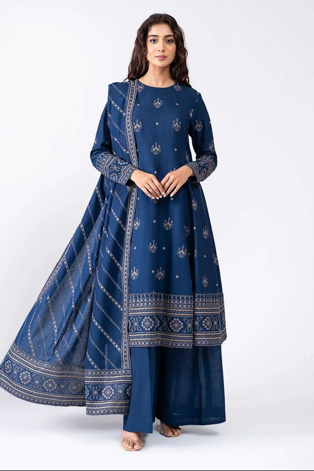 Woman wearing a blue traditional outfit with intricate patterns on a white background